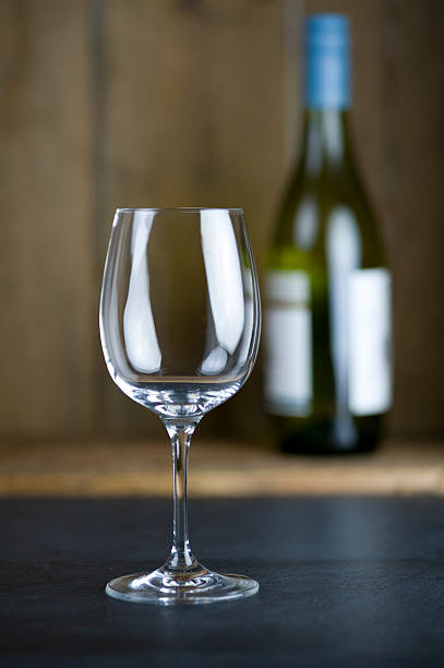 Empty wine glass with bottle in background stock photo