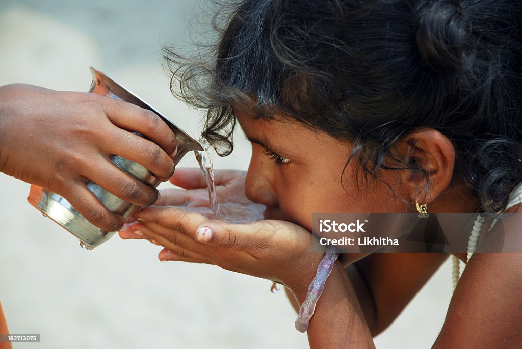 Child in solidarity act provides water to another Young girl drinking water Water Stock Photo