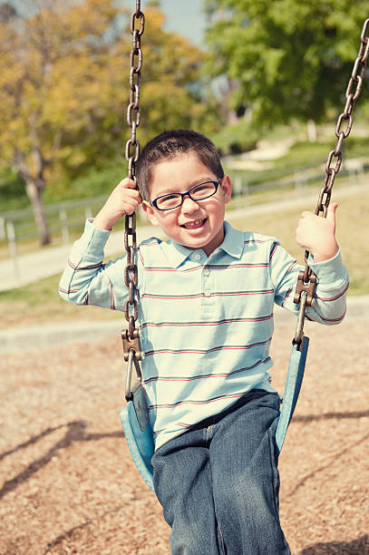 istock happy boy smiling at camera on swing 182713257