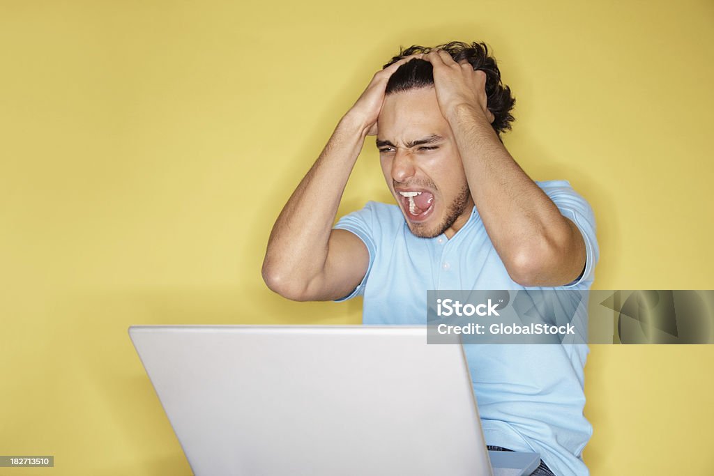 Frustrado menino usando o laptop contra Fundo amarelo - Foto de stock de Homens royalty-free