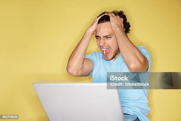 Foto de Frustrado Menino Usando O Laptop Contra Fundo Amarelo e mais fotos de stock de Homens