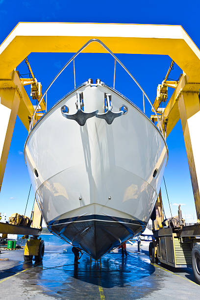 seasonal mending large luxury motor yacht hanging from a shipyard crane and being washed with a high pressure water cleanerCHECK OTHER SIMILAR IMAGES IN MY PORTFOLIO.... dry dock stock pictures, royalty-free photos & images
