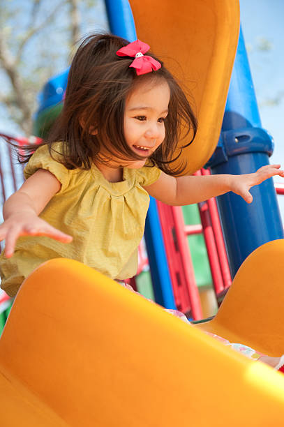istock happy cute girl going down slide 182714048