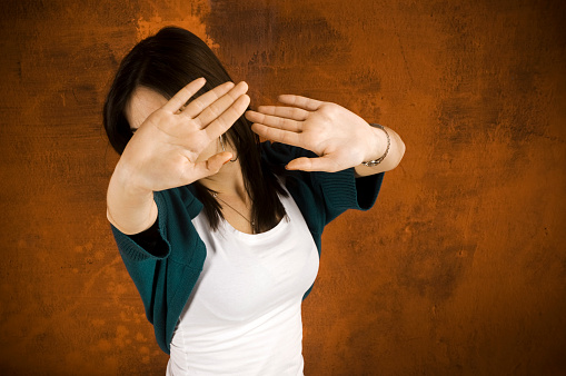 Young woman doesn't want to be shooted and showing her palms against the camera