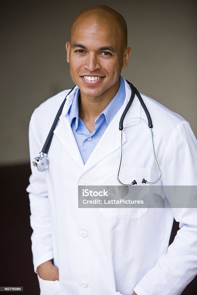 Smiling African Asian young doctor with hands in pockets African Asian descent young man wearing lab coat and stethoscope 20-29 Years Stock Photo