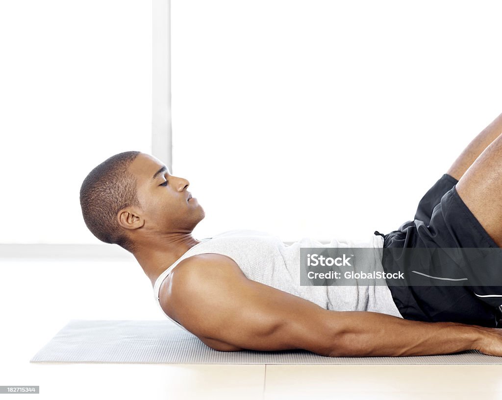 Jovem homem deitado no tapete de yoga e exercícios - Foto de stock de Deitado de costas royalty-free