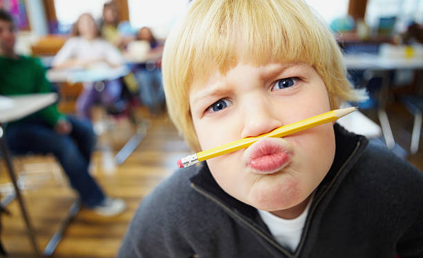 istock Mischievous school boy balancing a pencil on the nose 182715614