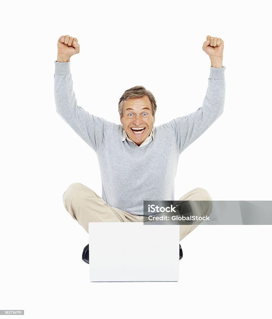 Achievement - Old man with hands raised using laptop Senior man using a laptop and gesturing an excitement with hands raised on white Cut Out Stock Photo