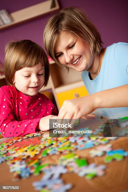 Madre Aiutando Sua Figlia Con Puzzle - Fotografie stock e altre immagini di Puzzle - Puzzle, Bambino, Donne