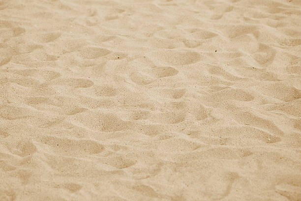 A close-up of sand on a beach with numerous footprints stock photo