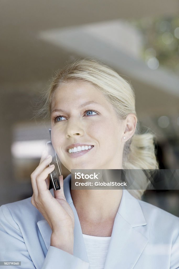 Bella femmina Imprenditore utilizzando un telefono cellulare al lavoro - Foto stock royalty-free di 25-29 anni