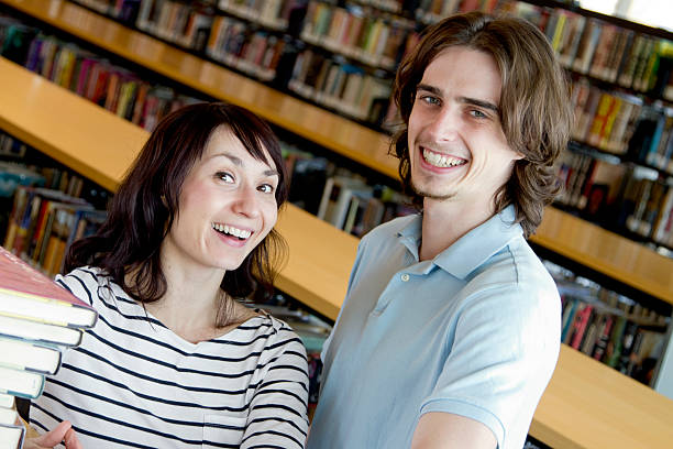 istock Young Couple with a Stack of Books at the Library 182719536