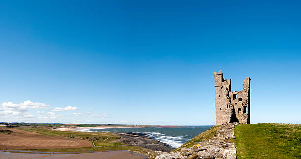 lilburn turm schloss dunstanburgh und der küste von northumberland panorama, großbritannien - castle famous place low angle view england stock-fotos und bilder