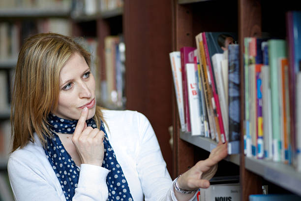 istock Attractive young blonde woman browsing books in library 182720397