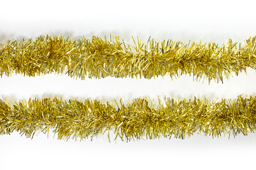 Two gold shiny Christmas tinsel close up isolated against a white background, flay lay, top view.