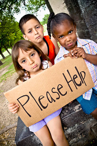 istock Sad Children Holding a Please Help Sign 182721685