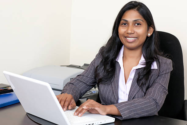 Indian business woman working on laptop. Happy woman secretary typing on laptop in the office. sri lanka business stock pictures, royalty-free photos & images