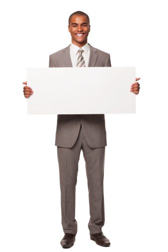 Portrait of a young adult businessman holding a blank sign and smiling at the camera. Isolated on white. Vertical shot.