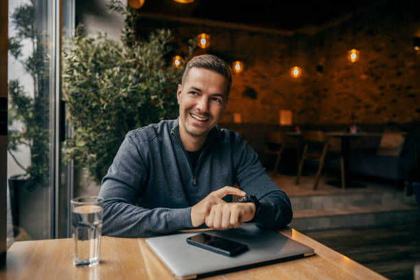 istock A happy man is checking time on wristwatch while looking away in cafe. 1827224850