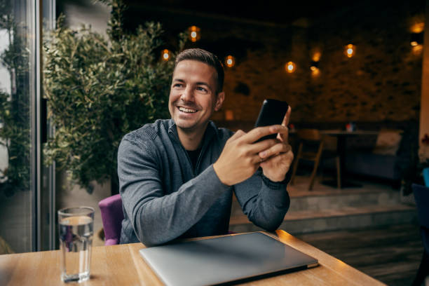istock A happy man is using phone in cafe and looking away. 1827227152