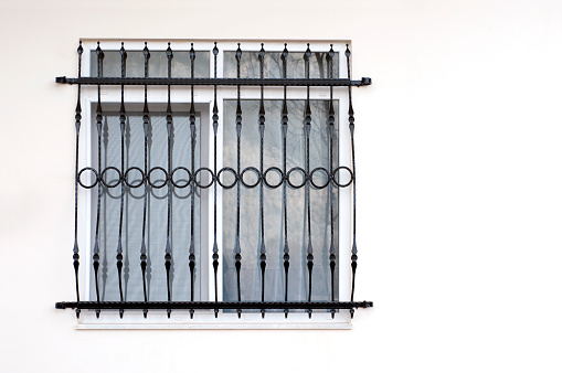 Window with decorative bars on a white wall