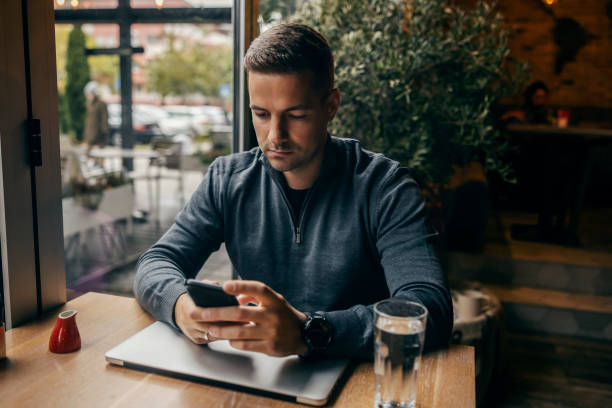 istock A man sitting in a coffee shop and using his phone. 1827230377
