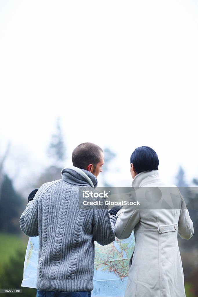 Pareja joven buscan indicaciones en el mapa - Foto de stock de 20-24 años libre de derechos