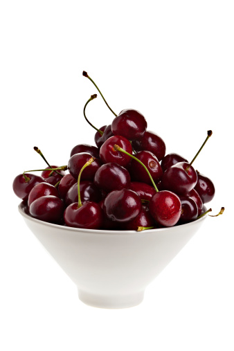 A white bowl of cherries on a white background.