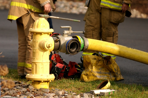 Fire fighters adjust the water pressure on a yellow fire hydrant