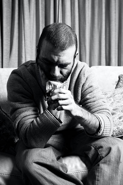 istock depressed man drinking bourbon - monochrome 182725386