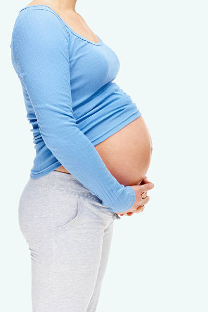 istock Mid section of a pregnant lady standing against plain background 182725829