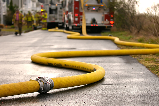 Long fire hose snakes it way from the hydrant to the pumper/engine truck in the distance