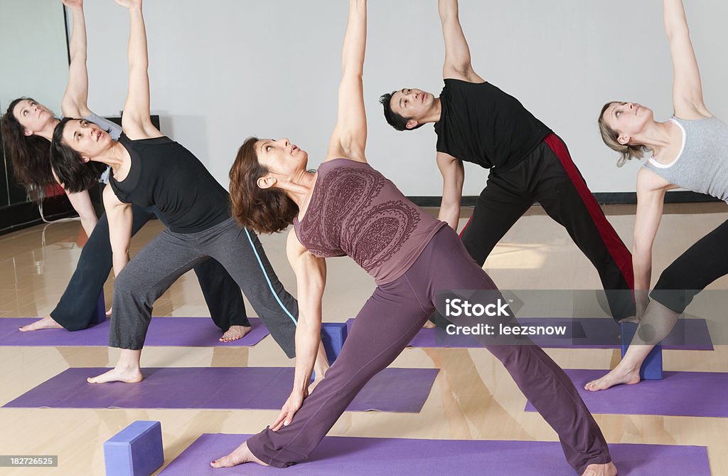Classe fazendo ioga de grupo Postura de triângulo estendida - Foto de stock de Adulto royalty-free