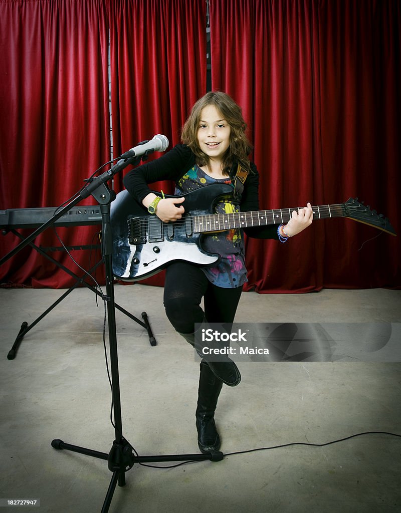 Child singing and playing on stage Young child playing guitar. Vignetted.More: Girls Stock Photo