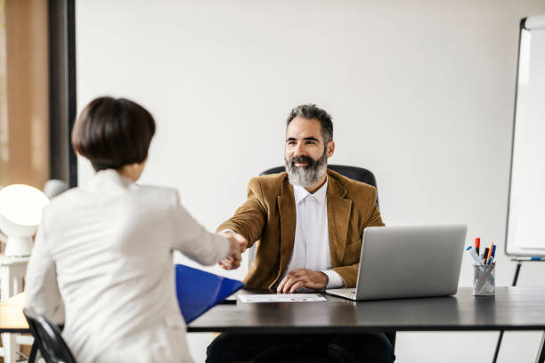 istock A businessman is shaking hands with future associate while sitting at the office in company. 1827284825