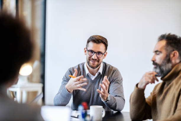 istock A businessman is sitting in boardroom with team and explaining his ideas. 1827286368