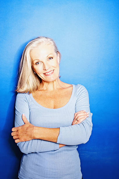 istock Mature woman with hands folded against blue background 182728738