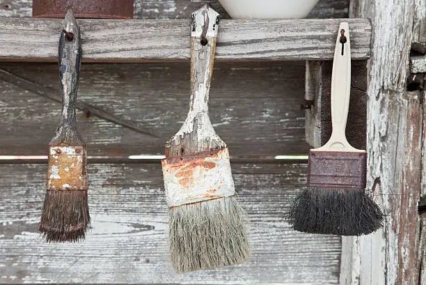 Used Paintbrushes hanging as found in abandoned tool shed in West Texas