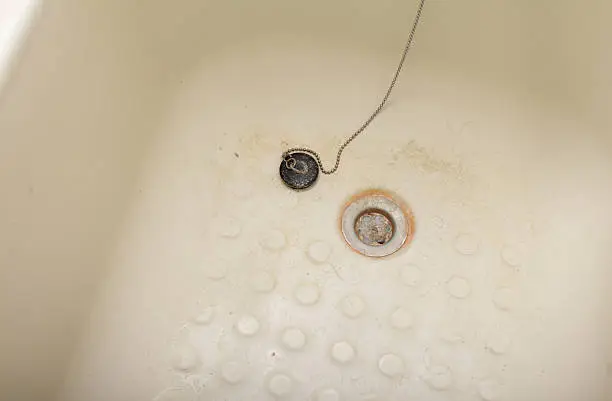 dirty bath with clogged plughole - hairs, limescale, mould