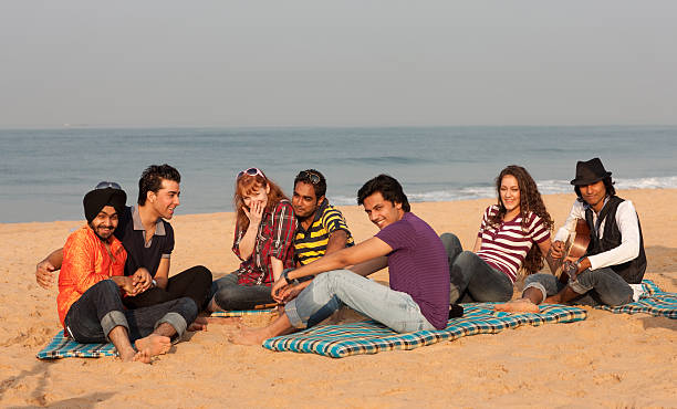Good time on the beach in India "7 young people having fun on the beach, playing cards and doing some jamming on guitar and flute." beach goa party stock pictures, royalty-free photos & images