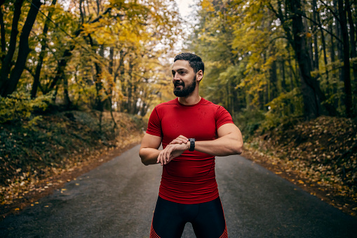 A runner is using smart watch fitness app in nature after workout.