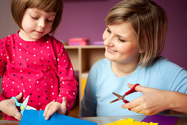istock Mother and child play with scissors and construction paper 182730563