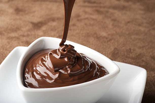 geschmolzener schokolade wird eingeschenkt - chocolate sauce stock-fotos und bilder