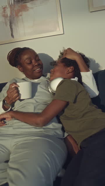 Female Hospital Worker Relaxing on Couch with Son after Night Shift