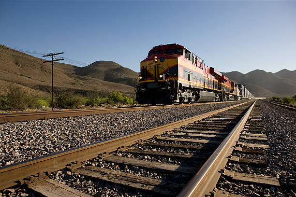 Angled view of train tracks with oncoming freight train stock photo
