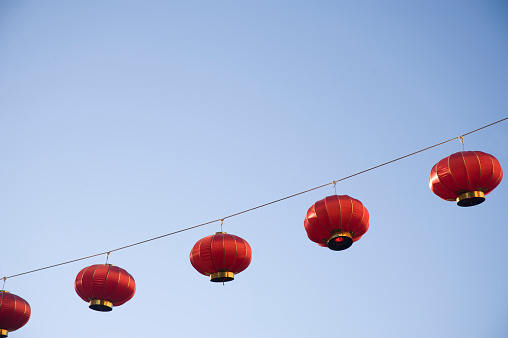 Bright red Lanterns are illuminated by the early morning light against a clear blue sky