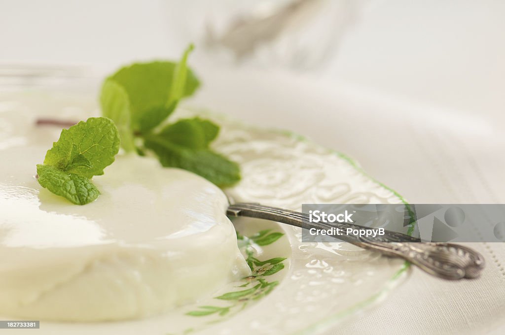 Plate of Creamy Panna Cotta with Spoon Antique plate of creamy panna cotta dessert with fresh mint garnish Antique Stock Photo