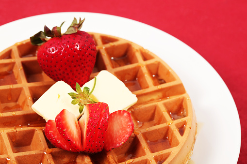 Belgian Waffle with strawberries, butter and maple syrup.