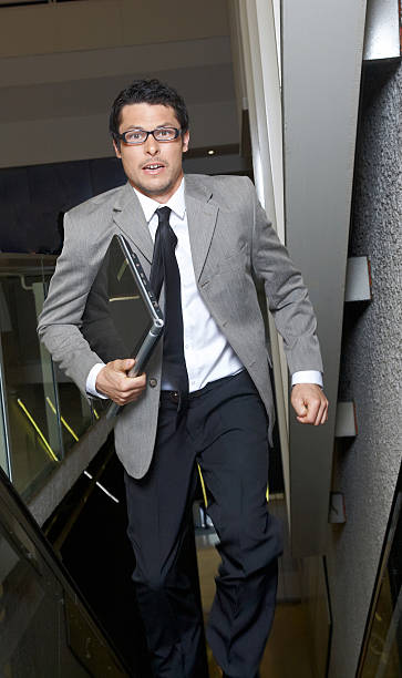 istock Young businessman running up escalator 182733590
