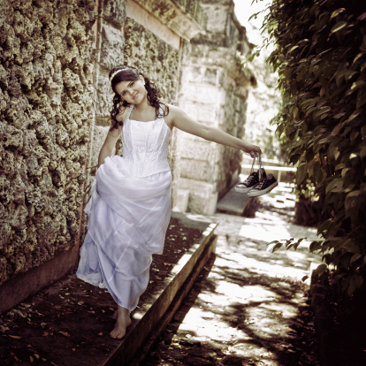 young girl walking barefoot while holding a couple of canvas tennis shoes around viscaya gardens - during her quinceanera photo-shoot